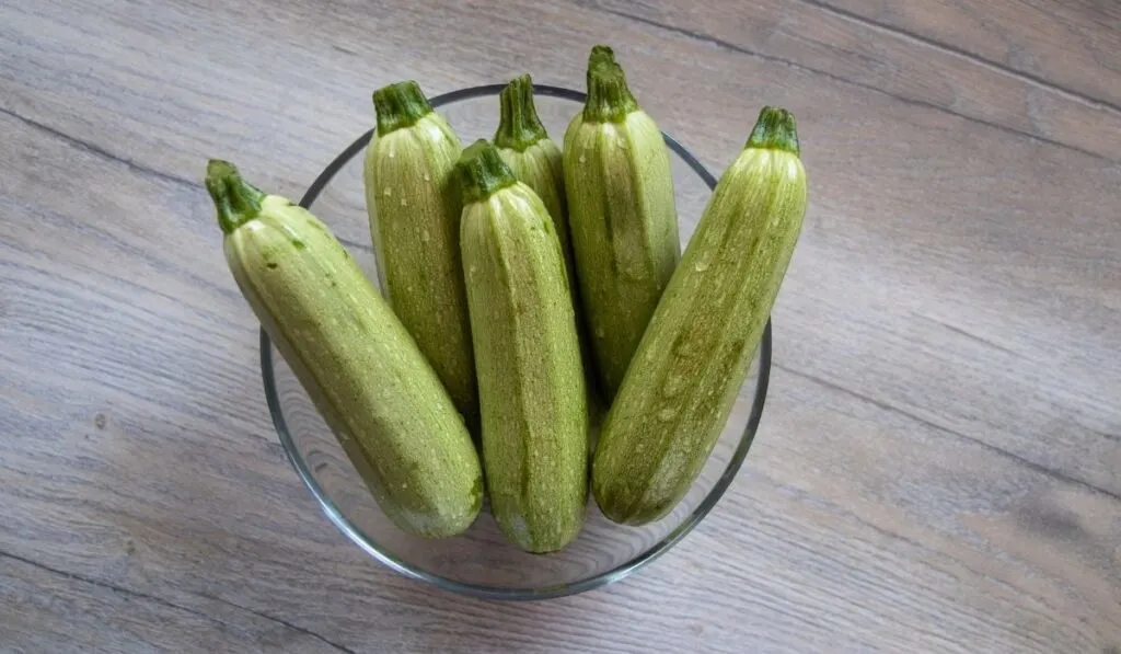 small, light green zucchini in a clear bowl on the table