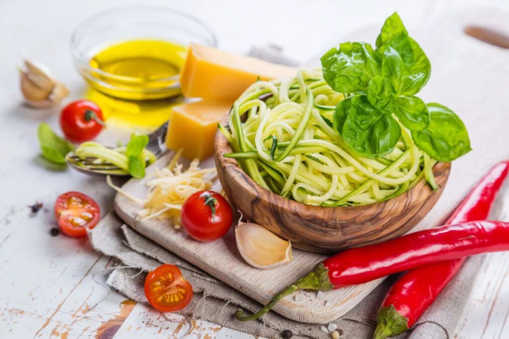 zucchini pasta in a wooden bowl with the ingredients and spices