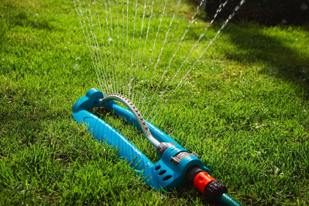 Oscillating Lawn Sprinkler turned on spraying water to the grass