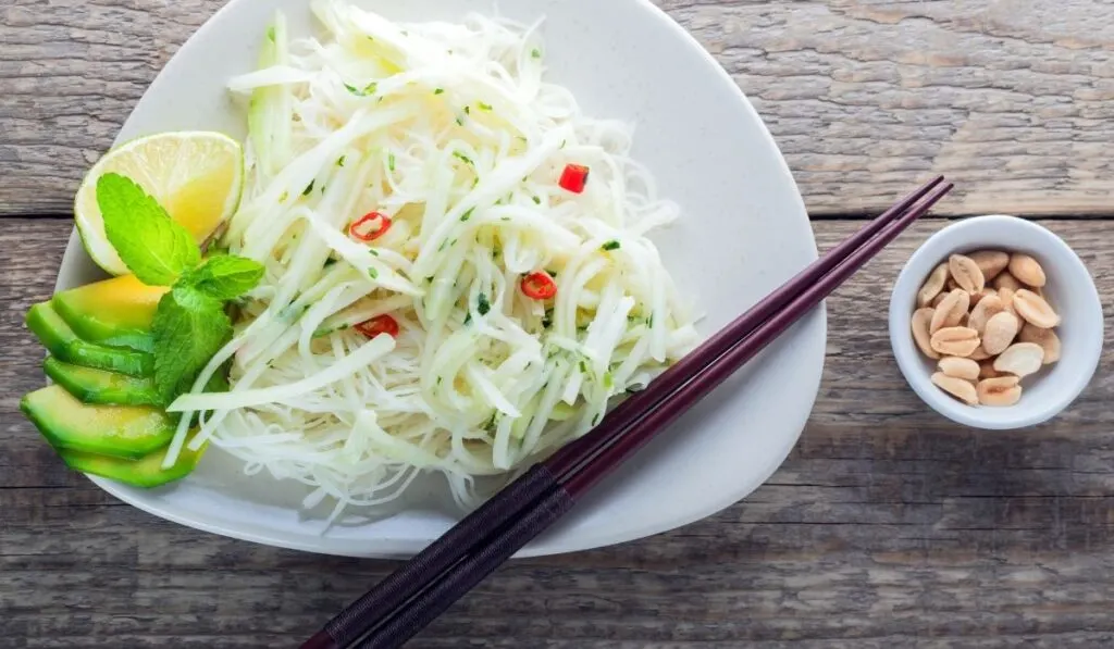 spicy Kohlrabi Noodles with sliced lemon and avocado