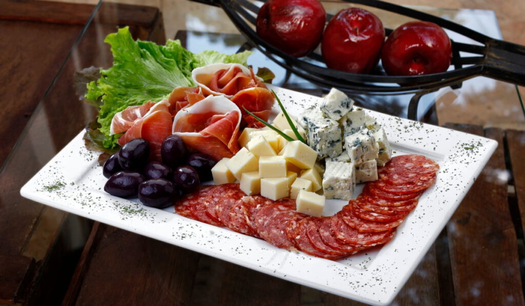 different cold cuts, cheese, olives on a white plate