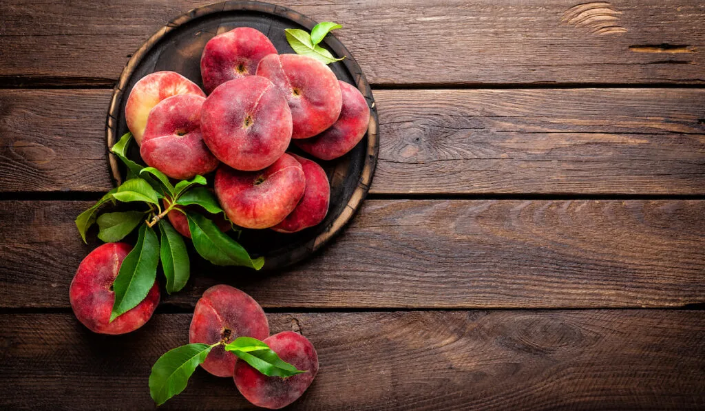donut peaches with leaves on wooden background 