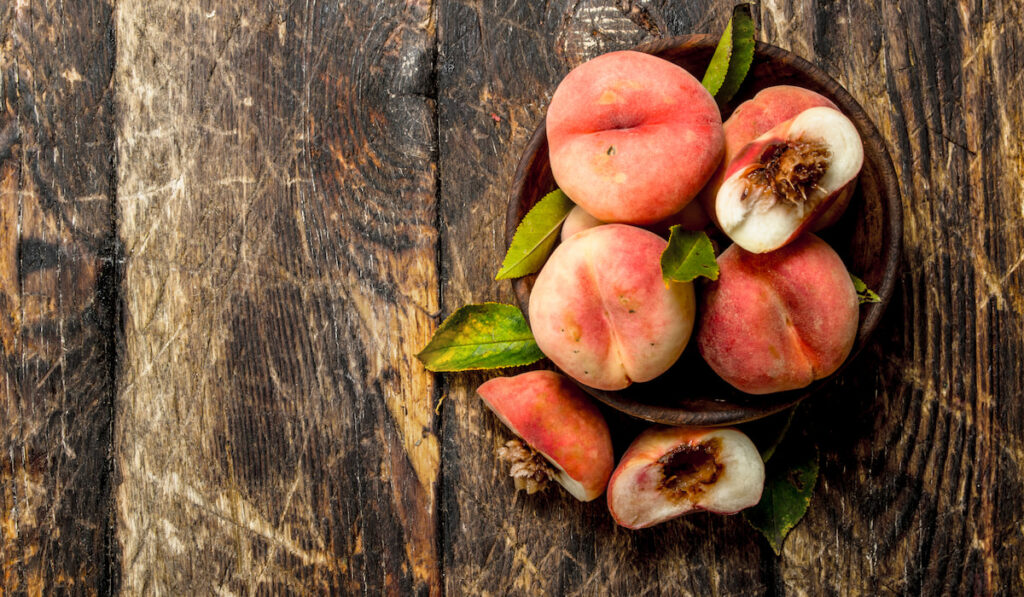 Fresh peaches in a bowl on wooden table