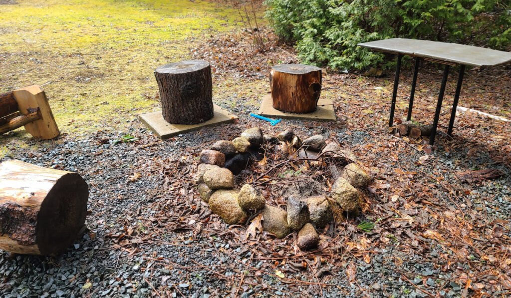 A closeup of a firepit with different types of seats setup around it in the yard
