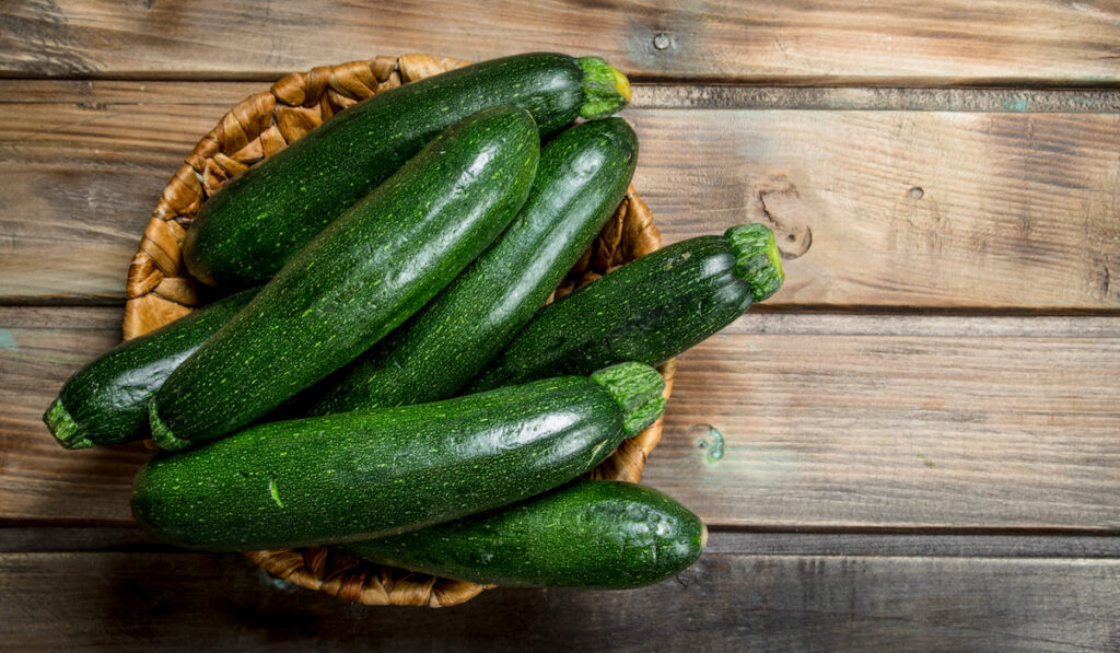 Fresh zucchini in the basket on wooden background