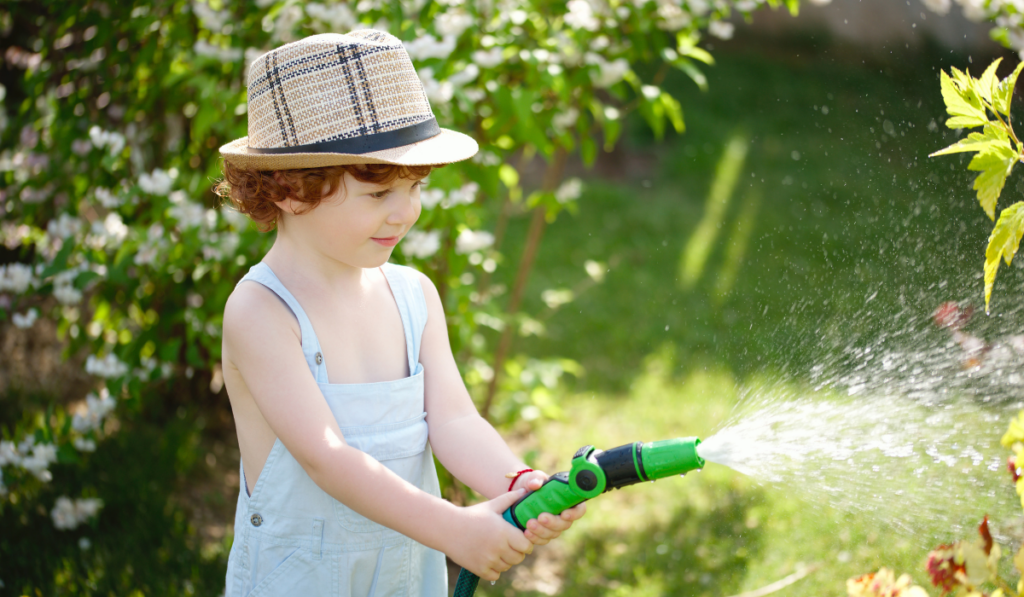 little boy watering the garden with hose
