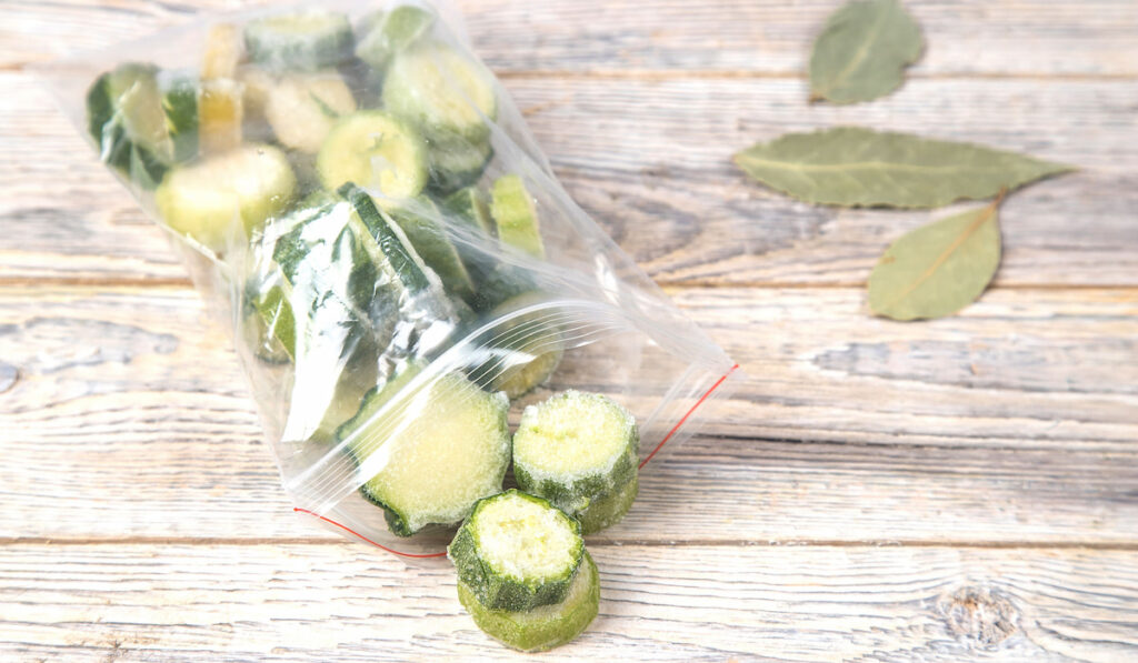 Frozen zucchini in Ziploc bag on wooden table