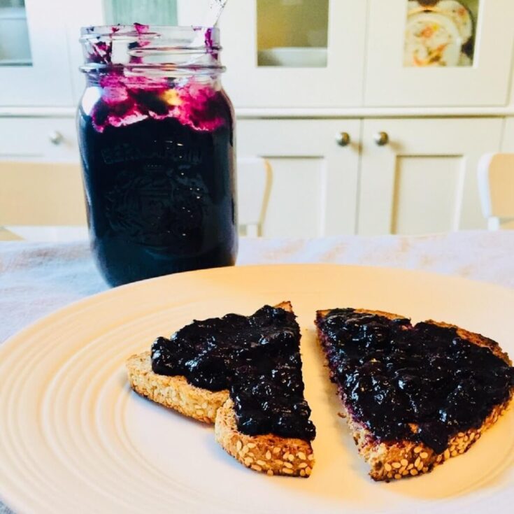 low sugar freezer jam spread on toast with jam jar in the background