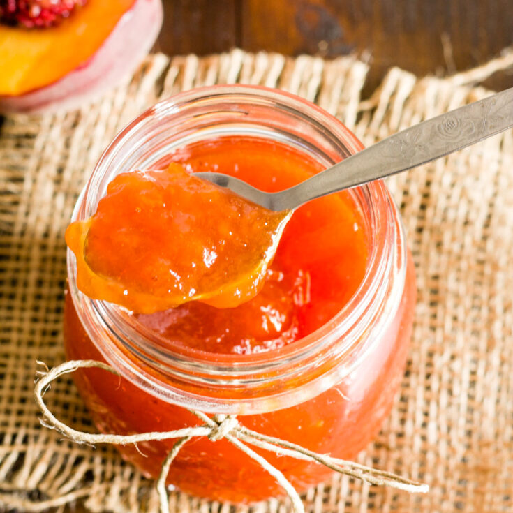 spoonful of peach jam being lifted out of a glass jar