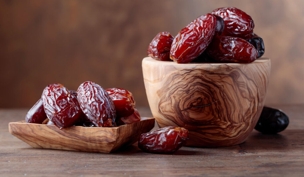 Juicy dates in a bowl on an old wooden table