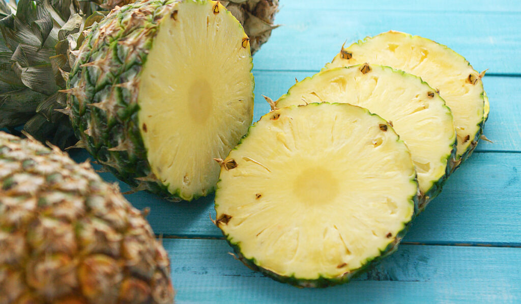 Slices of fresh pineapple on blue wooden table
