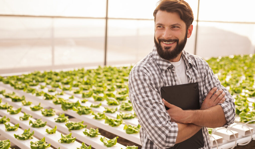 Happy gardener leaning on hydroponic table