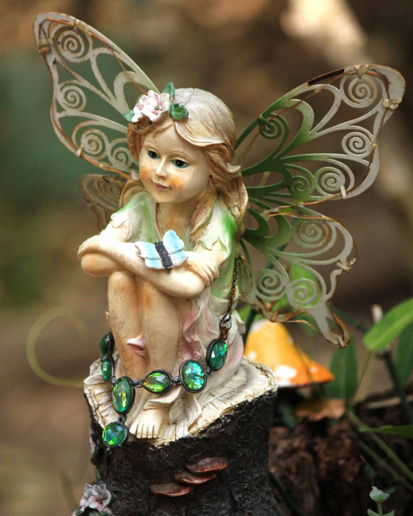 Statue of a little fairy sitting on a log in the garden