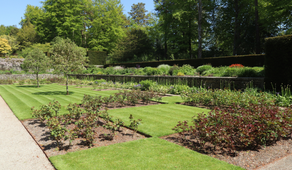A gravel path runs alongside a lawn, flowerbed patchwork in the formal gardens