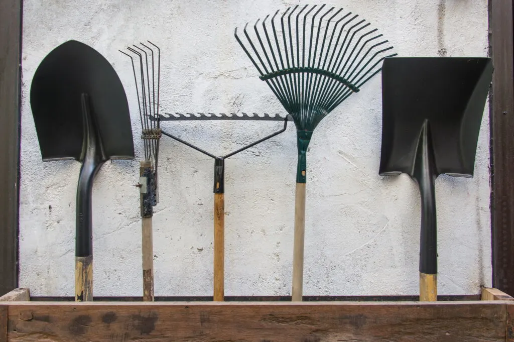 gardening tools, spade, fork and rake on cement wall 