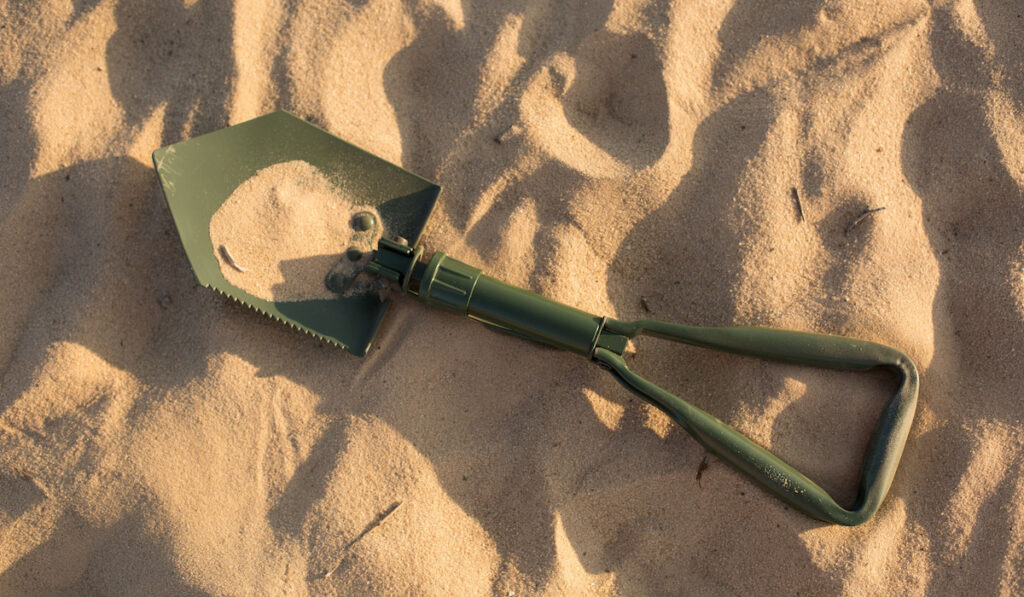 green Folding Shovel on the sand