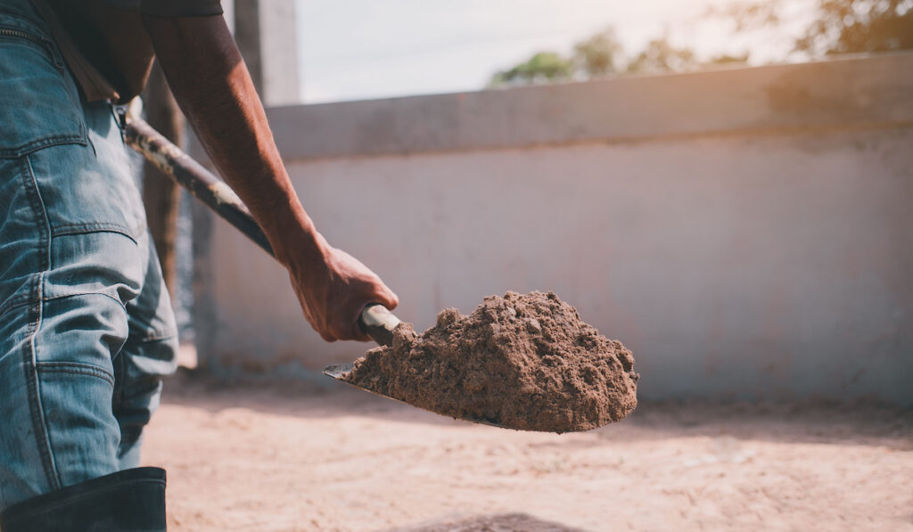 man using scoop shovel to dig soil on a construction site