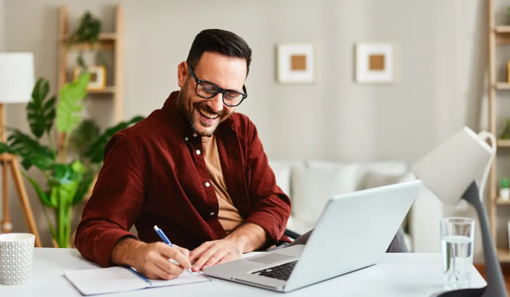man working at home with laptop and papers on desk