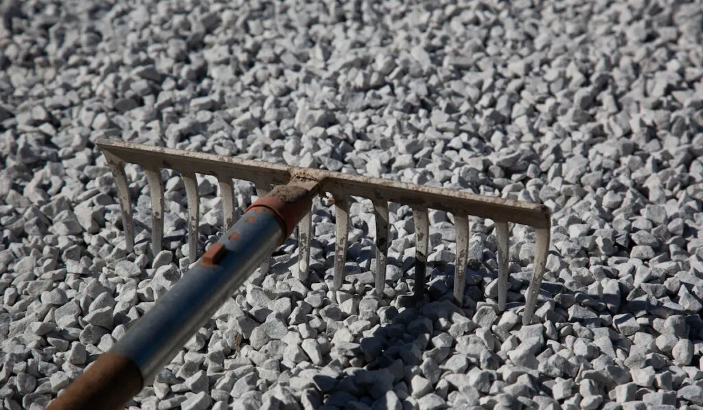 metal rake on the ground with crushed stones