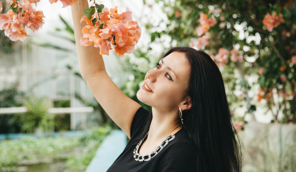 Beautiful woman smelling bougainvillea flowers in the garden
