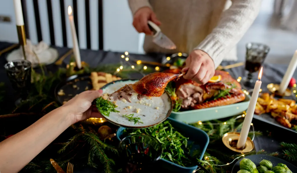man cuts off and takes a piece of the Christmas Turkey
