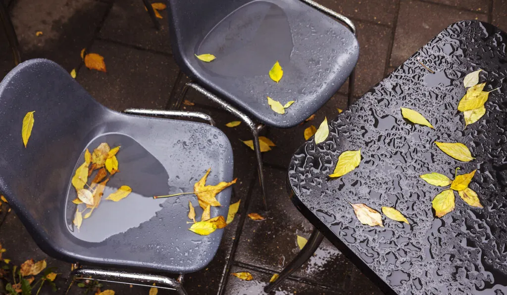 Messy and rainy plastic cafe chairs and table in the garden