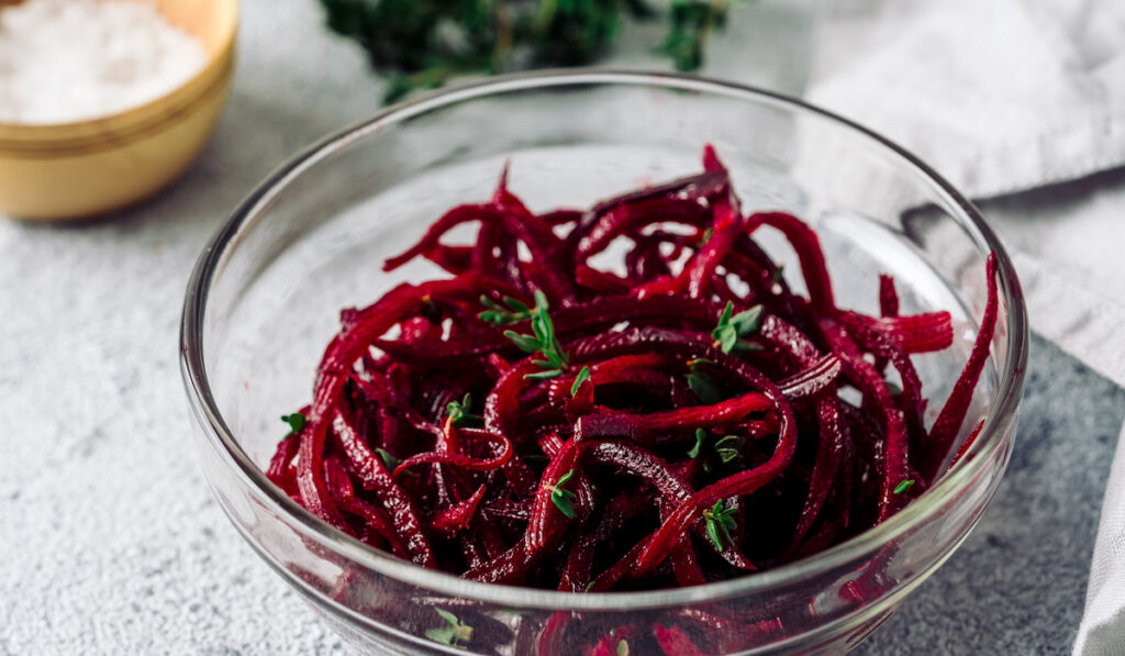 Raw beetroot noodles in a bowl on grey stone background