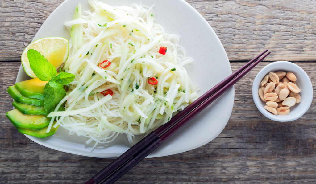 Spicy kohlrabi noodles, dressing: fish sauce, vinegar rices, lime, garlic and ginger on a plate