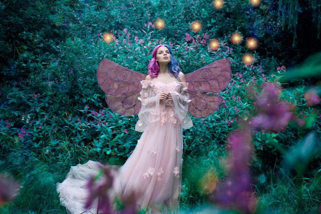 Art photo of a fairy fairy in a pink dress in the forest with fireflies
