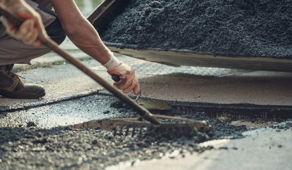 Retro image of two workers working together to lay new asphalt using a rake