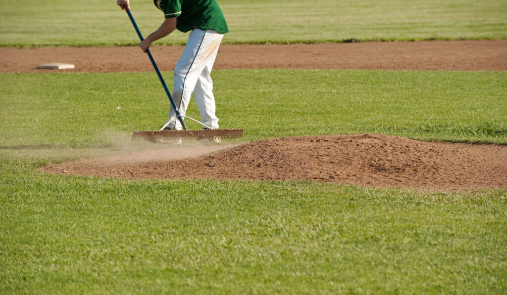 a baseball player rakes smooth the pitcher's mound