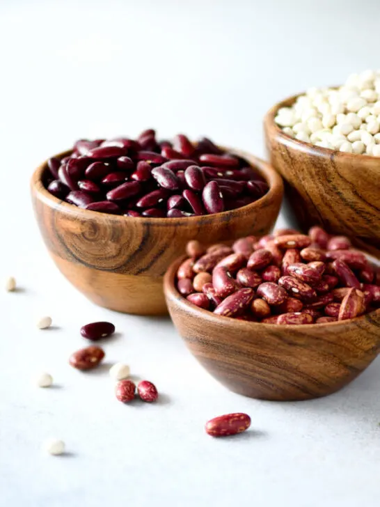 Different types of beans in a wooden bowl white background