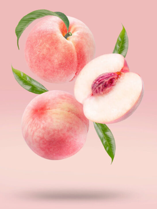 three fresh white peaches floating light pink background